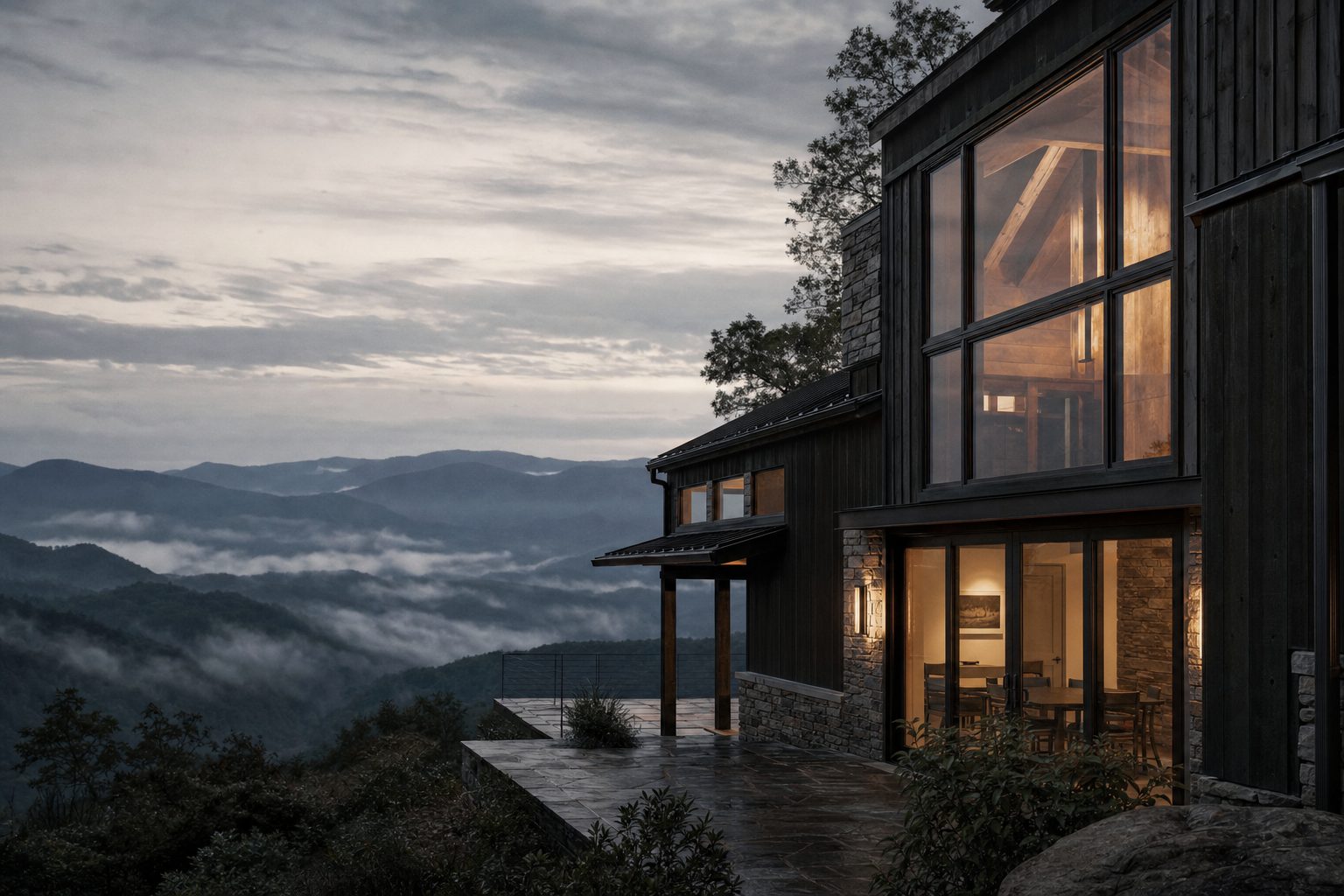 Modern cabin with lit windows on a North Georgia ridge at dusk, fog in the valley below